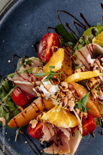 Quadro em tela Close-up of a fresh salad featuring sweet persimmon slices, delicate prosciutto, mixed greens, nuts, and soft cheese, drizzled with a light vinaigrette highlighting vibrant textures and colors