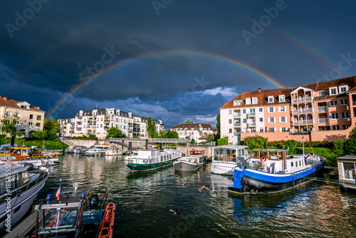 Town of Cergy in a stormy weather with a double rainbow over Port Cergy, France  