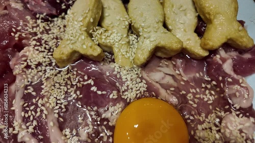 Vibrant Culinary Preparation Fresh Ingredients of Raw Meat, Bright Yellow Egg Yolk, and Sesame Seeds Create Delicious Food Presentation with Fish Shaped Cookies and Snacks