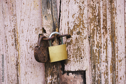 Rusty Vintage Padlock and New Brass Lock on Weathered Pink Wooden Door