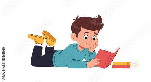 Young boy lies comfortably on his stomach on the floor while reading a red book with deep concentration.