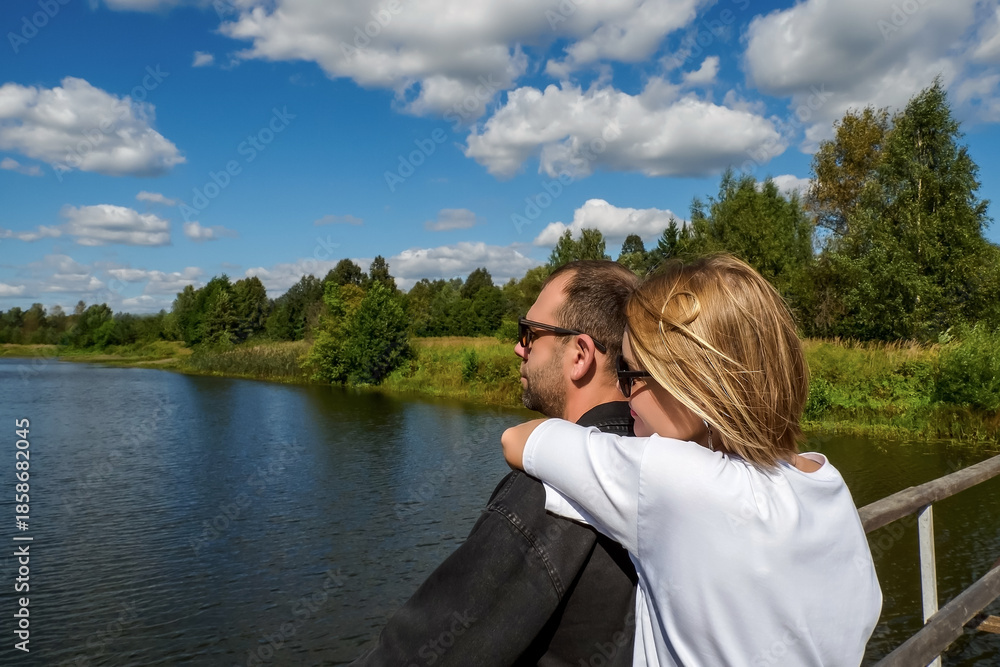 Fototapeta premium A happy couple. The couple's summer walk across the bridge: the concept of outdoor activities and romance.