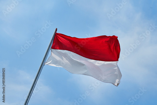 The flag of the Republic of Indonesia, called the red and white flag, flutters gracefully in the blue sky.