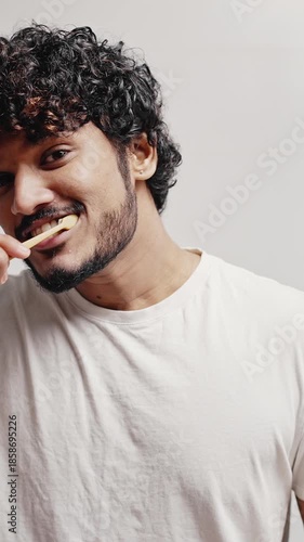 Young Indian man puts paste on brush to clean teeth at home