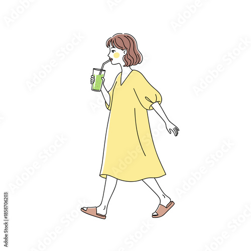 Young woman walking while drinking a green beverage in summer  