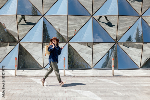 Woman walks near geometric glass wall in city