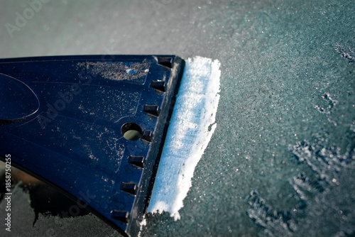 Hand scraping thick ice from a frozen car window showing winter vehicle care