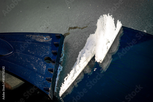 Hand scraping thick ice from a frozen car window showing winter vehicle care