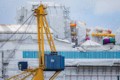 фотографія Photo of a large ship being constructed at a shipyard near the sea, captured from a distant vantage point