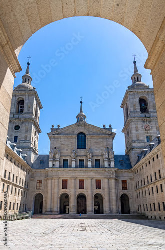 Εκτύπωση καμβά A sunny view of a symmetrical inner patio at El Escorial in Spain, featuring massive granite towers, uniform facades, and a grand basilica entrance