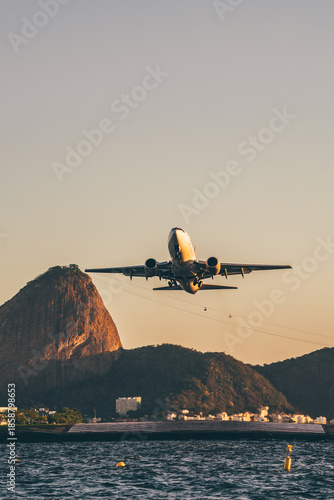 Tableau sur toile Passenger jet flying low over Guanabara Bay near Sugarloaf Mountain, Rio de Janeiro, Brazil, at golden hour