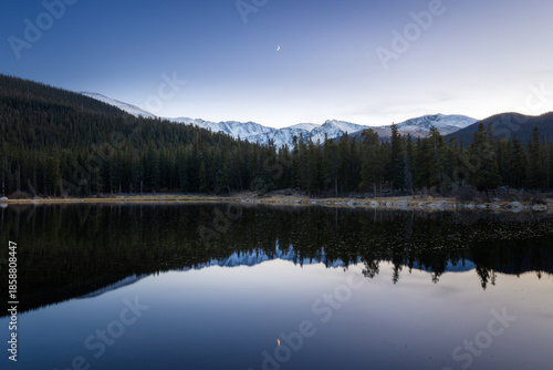 Snow mountain reflection with a crescent moon at dusk on Echo lake Idaho Springs, Colorado 