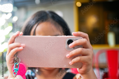 close up of little girl covering her face with hand holding smartphone
