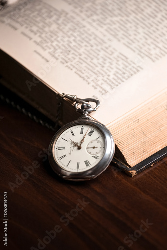 Vintage pocket watch on the background of an open old book.