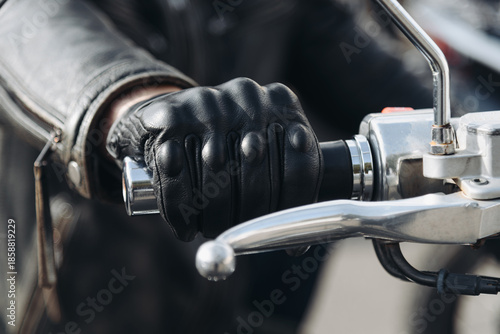 man hand in black leather glove on motorcycle handle, close up view, safety on road, riding motorcycle concept