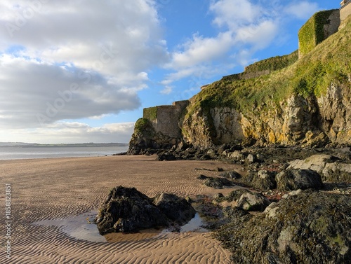 Rock pools at Duncannon Beach with moss covered fort on the hill in County Wexford, Ireland