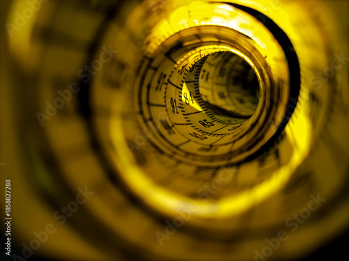 Coiled yellow measuring tape viewed from an end, creating a tunnel-like effect.