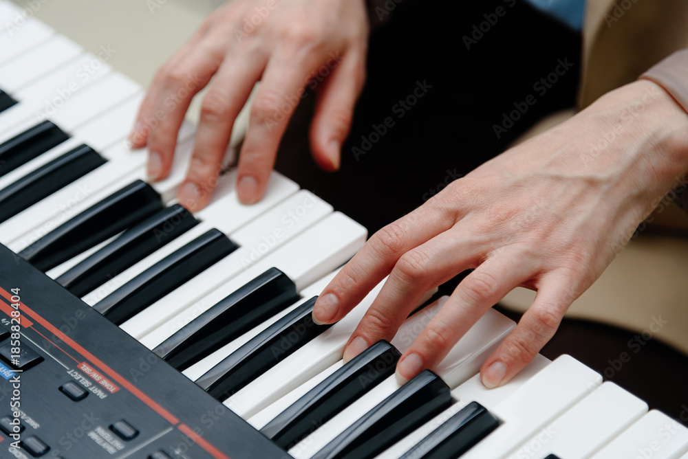Fototapeta premium female pianist hands on black and white piano keyboard, close-up view, young woman playing piano, professional musician