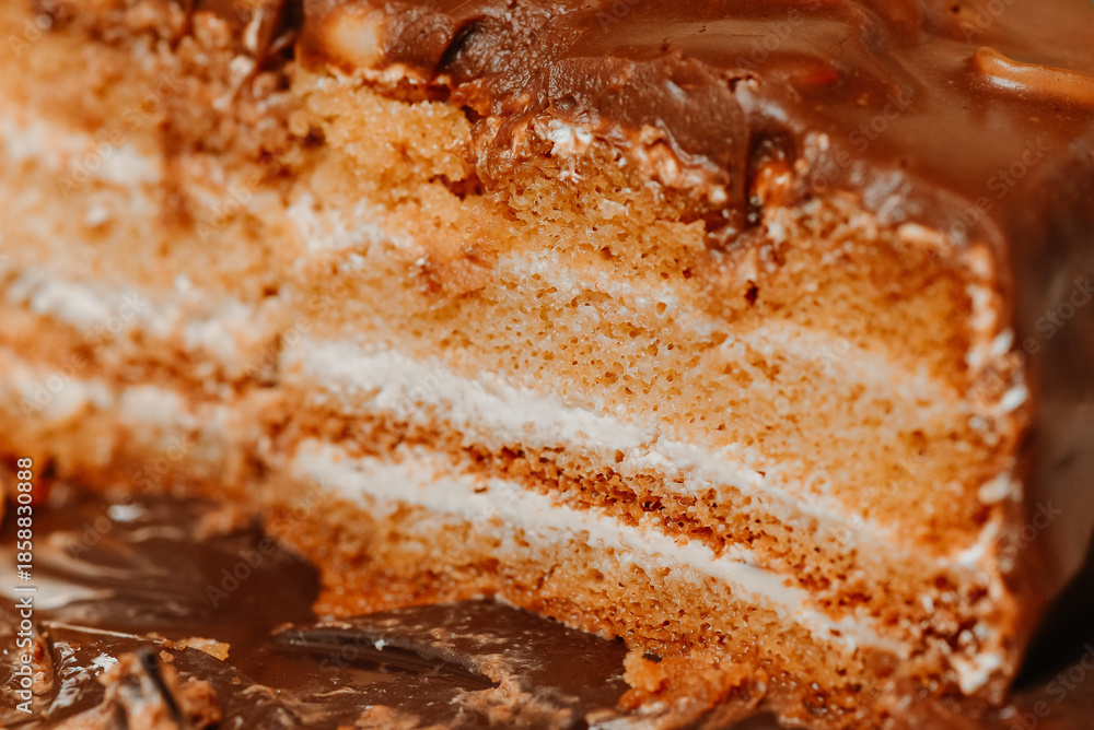 Fototapeta premium large brown sliced chocolate cake with cream and peanuts, sweet tasty food for holydays and celebrating, partly eaten, selective focus