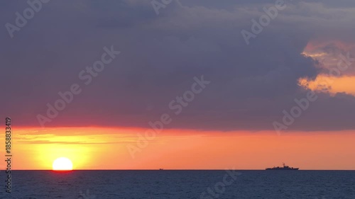 Sea sunset landscape with a sea ship against a dramatic sunset sky filled with clouds. Cinematic travel concept.