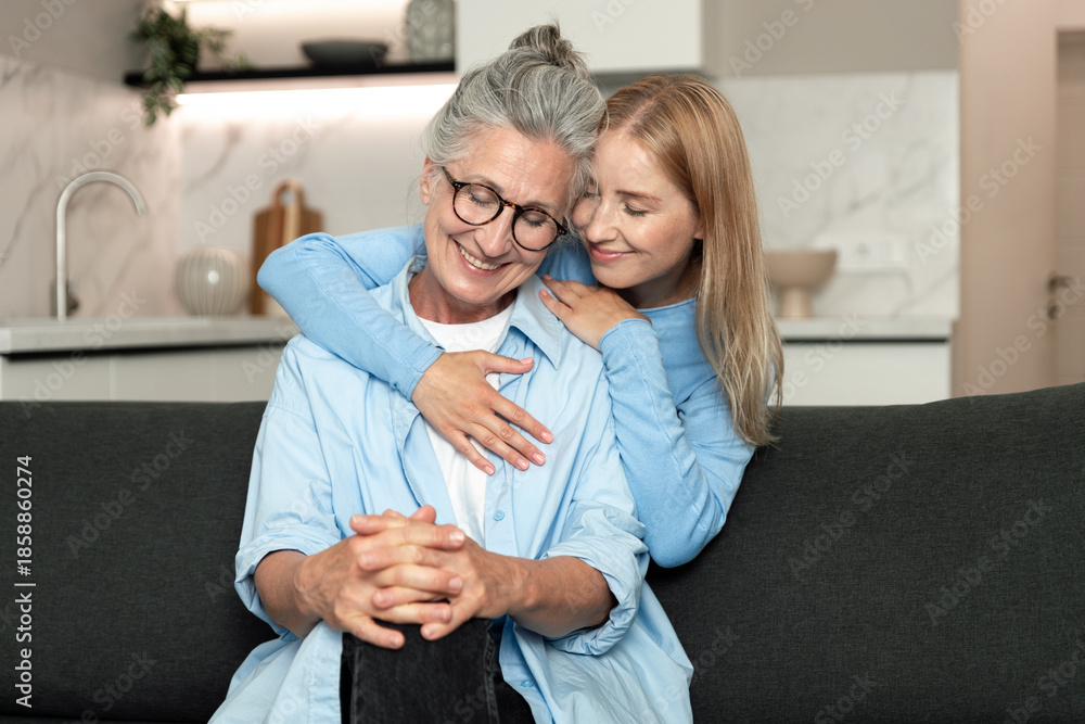 Obraz premium Elderly mother and adult daughter share a joyful moment in their cozy apartment