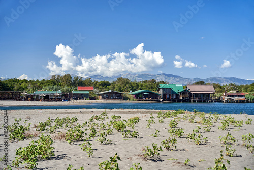 Beach and wooden summer cottages on the river near Bojana Island