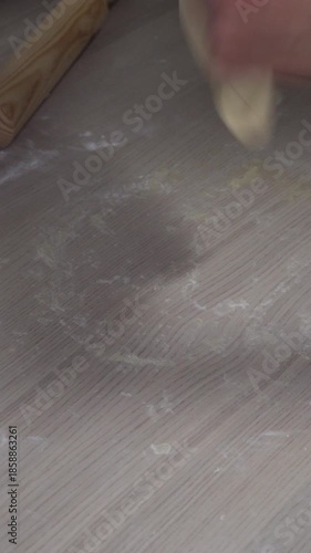 Rolling dough with wooden rolling pin, homemade pastry preparation, close up traditional cooking process on kitchen table, baking and food preparation. 9:16