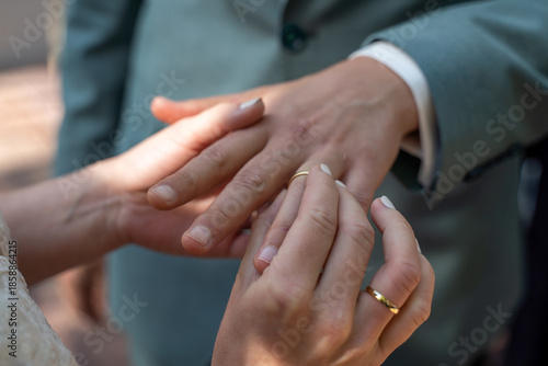 Hände eines Brautpaar beim Anstecken des Ehering nach der Ringübergabe auch Ringtausch während der Trauung im Rahmen einer Hochzeit im Standesamt