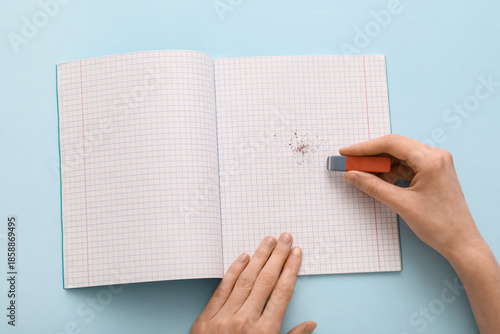 Photos Woman erasing something in notebook on blue background