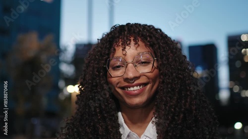 Portrait of a cheerful young African American woman with glasses in the city at night