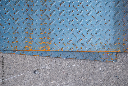 Imagen cenital de varias placas de metal color azul oxidadas en el suelo tipo textura