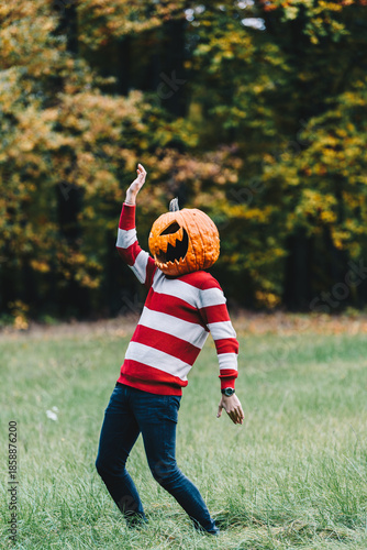 Playful Person with Pumpkin Head Dancing in Autumn Field