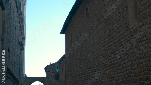 Revealing ancient arch in charming tuscan alley. Camera slowly tilting down revealing a picturesque alley with an ancient archway in a charming italian village, showcasing traditional architecture