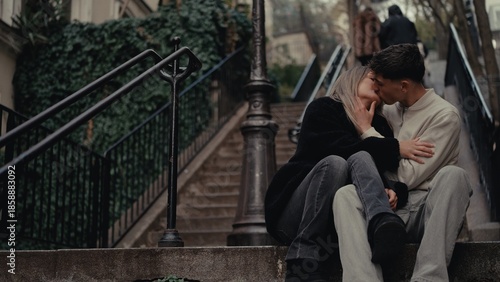 A romantic couple is kissing on the steps of Montmartre in Paris France The image captures a moment of love and affection in an urban setting ideal for travel and relationship themes.