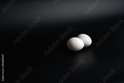 Minimalist breakfast concept with two white eggs on a small saucer, high key and low key light.
