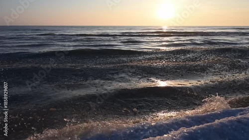 Waves from the icy waters of Lake Michigan splash along the frozen beach at sunrise.  Taken at Point Beach State Forest, Manitowoc County, Wisconsin.  