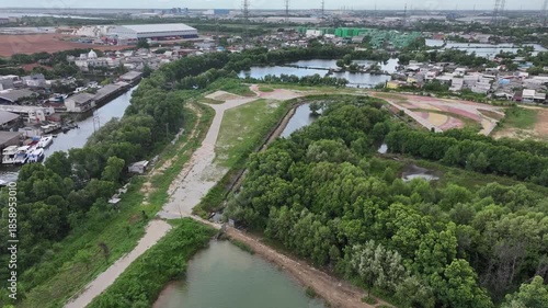 Aerial view of city streets, green trees, a lake, and tall buildings, under a clear blue sky.waduk marunda jakarta
