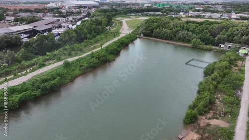 Aerial view of city streets, green trees, a lake, and tall buildings, under a clear blue sky.waduk marunda jakarta