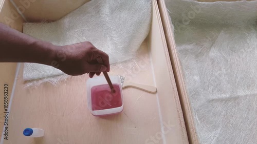 Stir resin in a container to make fiberglass waterproof for wooden planters.