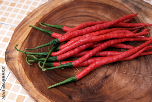 Fresh red curly chilies on a wooden cutting board in the kitchen table, Curly red chili peppers. ingredients, Flat lay, Top view.