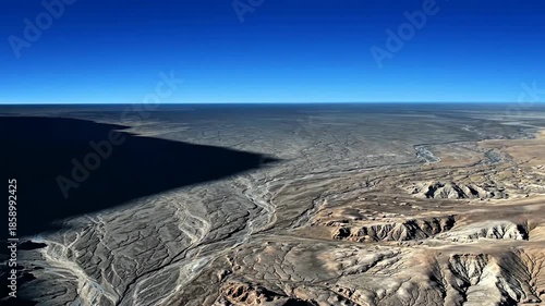 Desert landscape with dramatic shadow under blue sky.