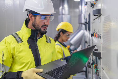 Focused engineering team reviewing HVAC blueprints in a professional industrial setting.	