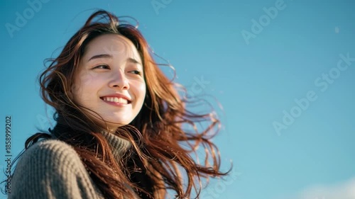 髪がなびく 笑顔の若い女性と青空（生成AI)