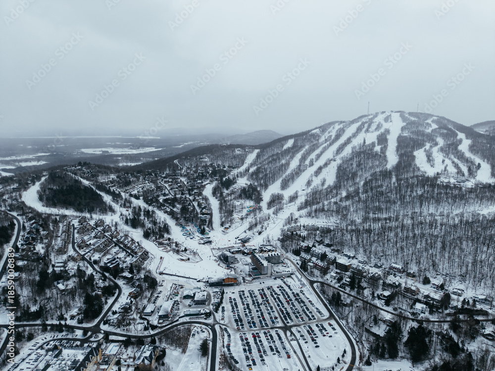 Fototapeta premium Aerial winter view of Bromont ski resort with snowy slopes, village and parking area in Quebec, Canada. g.