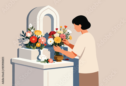 Person arranges colourful flowers near a memorial structure