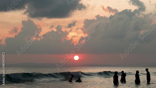 peaceful beach dramatic sunset with people playing in water