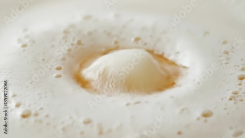 Liquid Pours Into Creamy Beverage Creating Circular Ripples Close Up