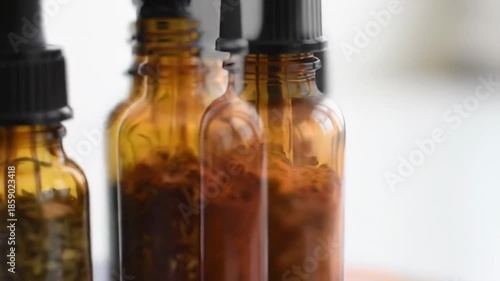 Wallpaper Mural A close-up photograph of four amber glass bottles with black caps, containing various colored liquids and herbs, on a white surface Torontodigital.ca