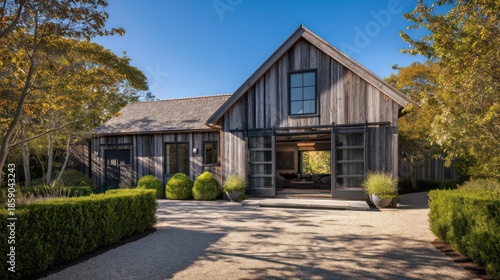 A rustic barn conversion home exterior with pitched roof sliding doors and weathered timber siding Gravel paths and