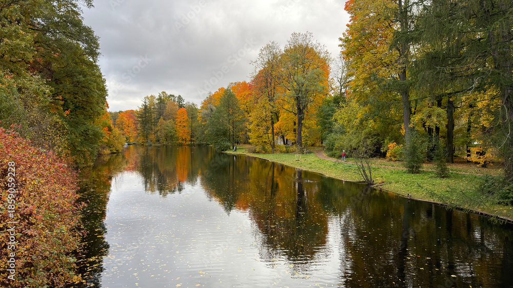 Fototapeta premium Serene autumn landscape with colorful trees reflecting in a calm river.